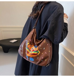 Detail of hobo bag featuring cartoon burger print and colorful polka dots on brown faux leather