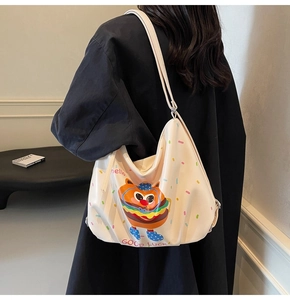 Detail of cream-colored burger tote bag with cartoon print shown on a model