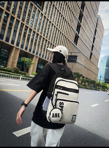 Side view of trendy black and white backpack with dual zippers and mini hanging pouch