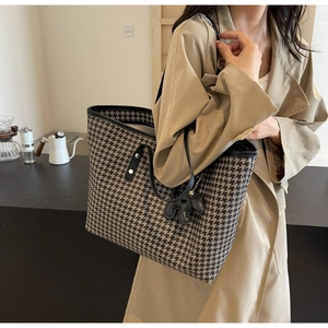 Detail of houndstooth tote bag with dog charm and leather trim on female model