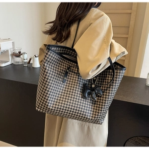 Detail of large houndstooth tote bag with black leather straps and dog charm detail