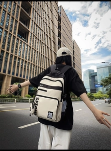 Outdoor shot of stylish off-white canvas backpack with black stripes and side mesh pocket