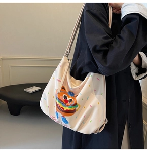 Detail of a creamy white tote bag with cartoon burger cat print and Good Luck slogan
