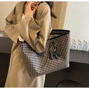 Detail of houndstooth tote bag with black leather trim and cute puppy charm pendant