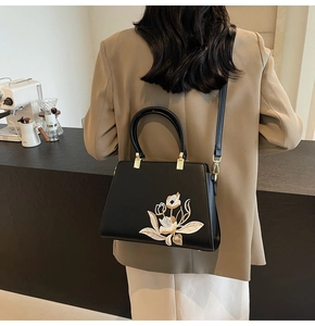 Elegant black embroidered handbag with floral details shown as a stylish crossbody bag