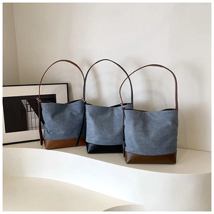 Detail view of denim bucket bags with faux leather trim in brown and black on display
