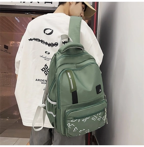 Detail view of green nylon backpack showing side mesh pocket and reflective strip