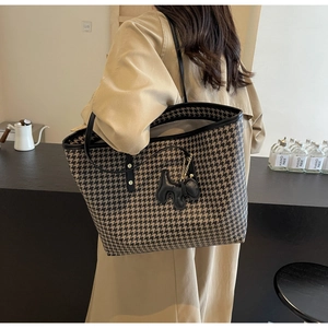 Detail of khaki houndstooth tote bag with black leather handle and puppy charm