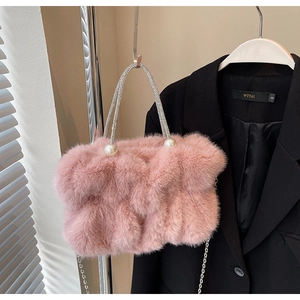 Detail van roze pluizige handtas van imitatiebont met parels en een strass handvat