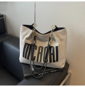 Detail of MICAORI canvas tote bag with leather trim and stylish metal chain strap