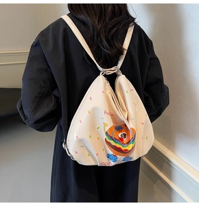 Rear view of a stylish beige burger cartoon backpack on a model in a casual setting