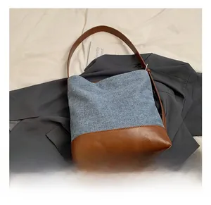 Detail of high-capacity bucket bag showing blue denim and brown leather patchwork texture