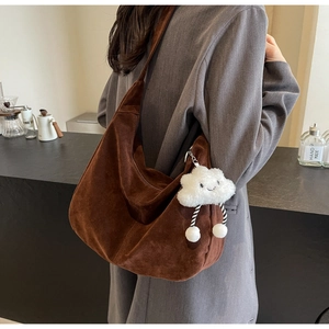 Detail of dark brown suede tote bag with a white plush cloud charm on the shoulder strap