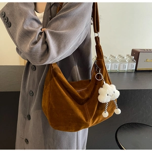 Detail of caramel brown suede hobo bag with cloud charm shown in a lifestyle setting
