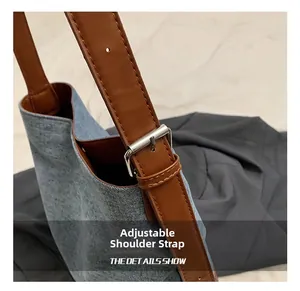 Detail view of the adjustable brown leather strap with silver buckle on a denim bucket bag