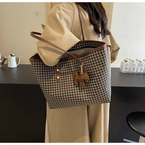 Detail of houndstooth tote bag with brown leather trim and a cute puppy charm