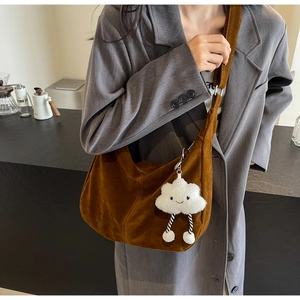 Detail of caramel suede hobo bag with a plush cloud charm on a grey blazer model