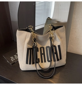 Detail of off-white tote bag featuring black leather trim and chain-link shoulder strap