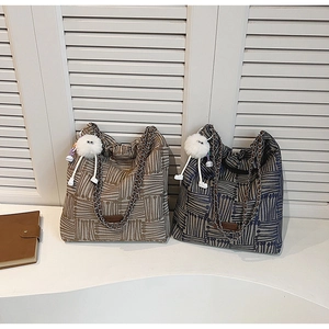Detail of canvas tote bags with chain straps and plush charm against white shutters