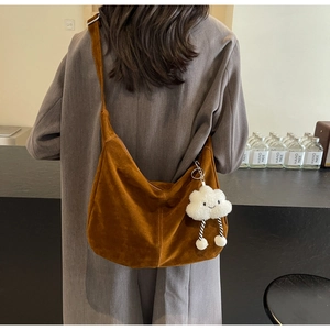 Detail of a brown suede tote bag with a plush cloud charm on a grey coat model