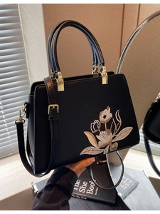 Elegant black leather handbag with floral embroidery, dual handles and gold hardware