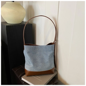 Detail of adjustable leather strap and denim patchwork on a minimalist bucket bag