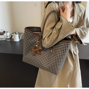 Close-up of houndstooth tote bag with brown leather handles and a puppy-shaped tag