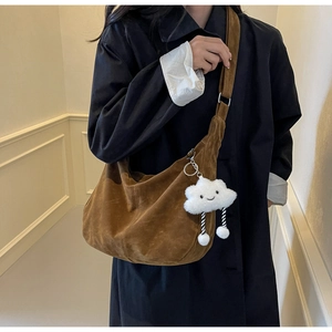 Detail of coffee brown suede crescent bag with a cute white cloud plush pendant