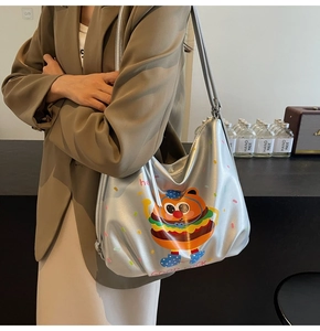 Silver tote bag featuring cartoon burger bear print worn with a casual brown blazer