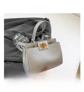 Detail of silver lychee texture bag with gold rotary lock on grey blazer background