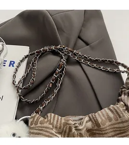 Detail of woven leather silver chain strap on a brown geometric pattern tote bag