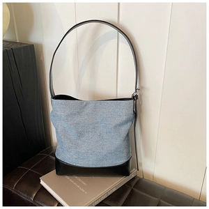 Detailed shot of denim and black leather bucket bag on a stylish book setting