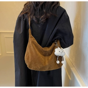 Detailed view of a brown suede large tote bag with a plush white cloud charm on strap