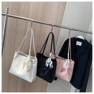 Close-up of quilted tote bags in cream, black, and pink with woven straps and silk scarves