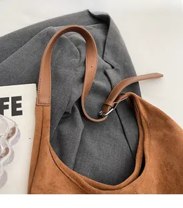 Detail of adjustable leather strap with silver buckle on brown suede hobo bag