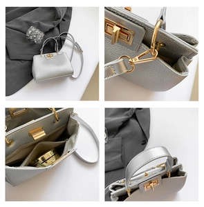 Detail view of silver tote bag showing golden lock, textured leather, and interior layout