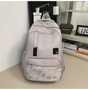 Detail of light grey nylon backpack showing multiple zipper layers and side pocket