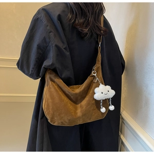 Brown suede tote bag with a cute cloud plush pendant worn over a black winter coat