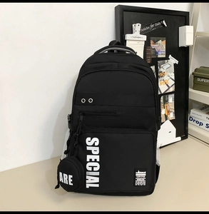 Detail view of black nylon backpack with multi-layer zipper pockets and side mesh pouch