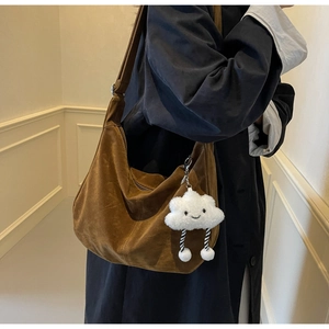 Brown suede hobo bag shown on shoulder with cute plush cloud charm detail