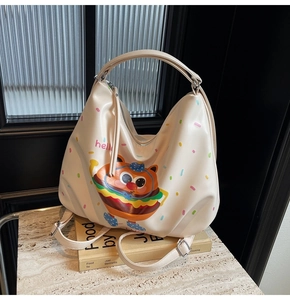 Detail of a creamy white cartoon hamburger hobo bag with hello print on a marble surface