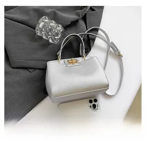 Detailed view of silver lychee leather handbag with gold twist lock and phone for scale