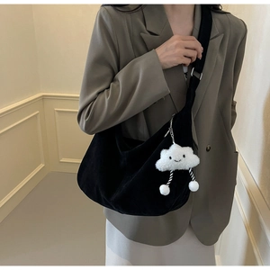 Close-up of black velvet hobo bag with a white plush cloud charm and wide strap