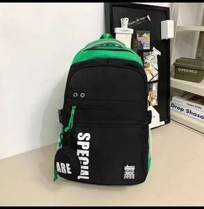 Detail of a black and neon green school backpack with side pockets and letter printing