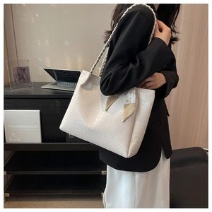 White embossed tote bag with woven straps and floral scarf detail shown in home office