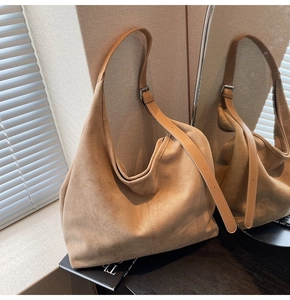 Detail of camel suede tote bag with leather strap and silver buckle in soft lighting