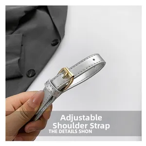 Detail of adjustable silver leather shoulder strap with a gold buckle and stitched holes