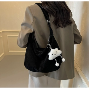 Detail of black suede tote bag with a white fluffy cloud charm and striped ribbons