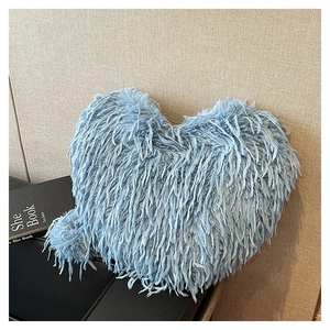 Détail d'un coussin shaggy doux en forme de cœur bleu clair sur une surface en cuir