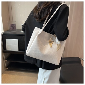 Detail of white leather tote bag with houndstooth texture and stylish scarf decoration